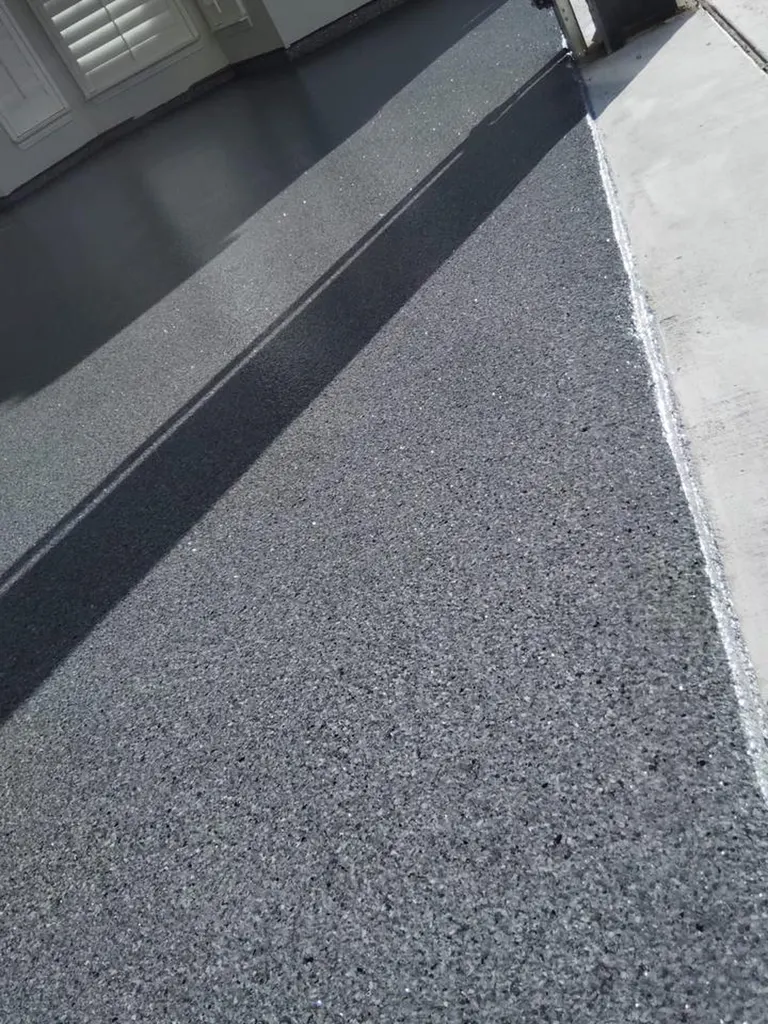 Charcoal gray speckled epoxy garage floor coating transitioning to outdoor concrete driveway