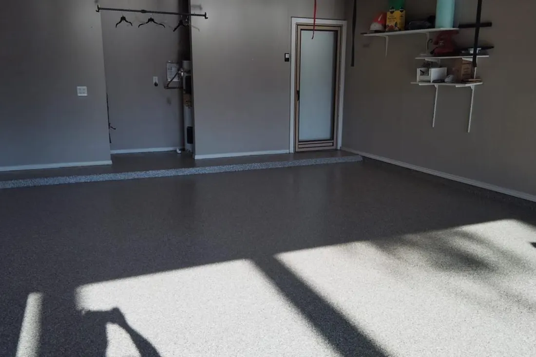 Spacious garage interior featuring glossy gray speckled coated concrete flooring and painted walls