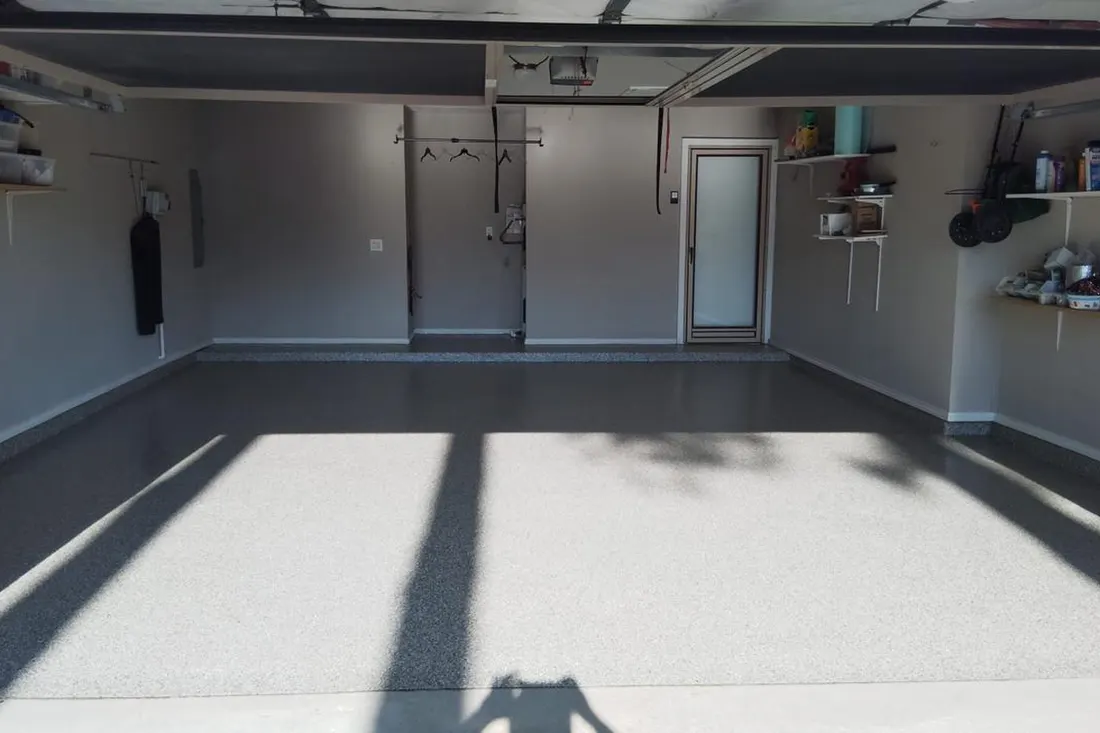 Empty residential garage with freshly coated glossy gray speckled epoxy concrete flooring