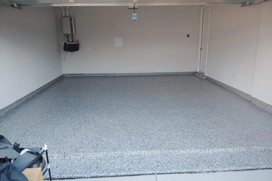 Empty garage with speckled gray epoxy coated concrete floor and white walls