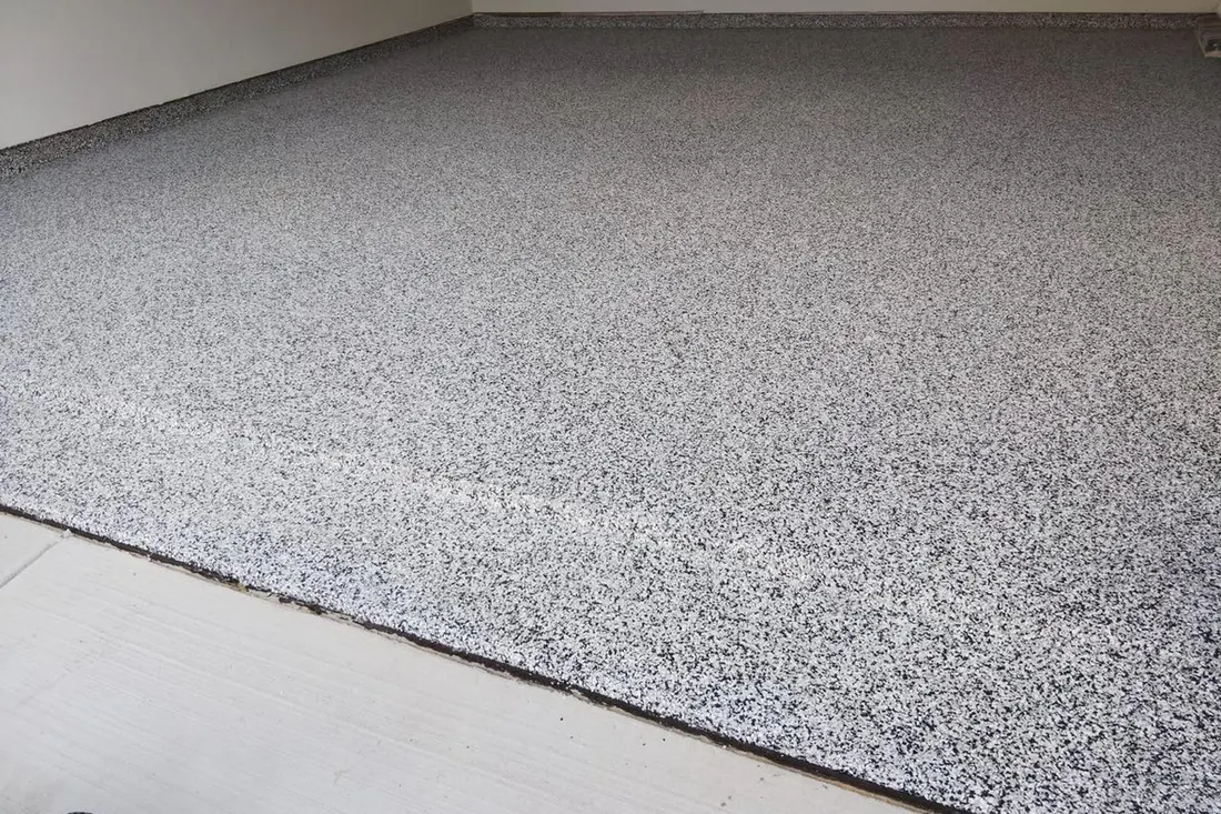 Textured gray and white speckled epoxy coating on a spacious indoor garage floor