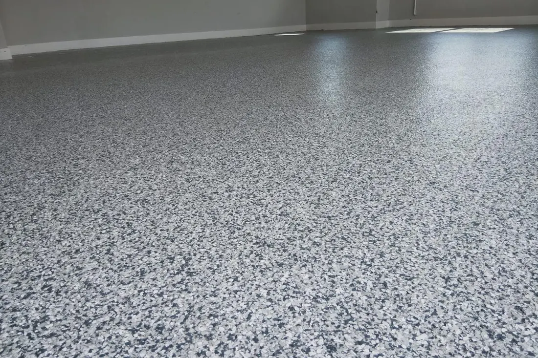 Speckled gray, black, and white epoxy flake coating applied to an indoor concrete floor