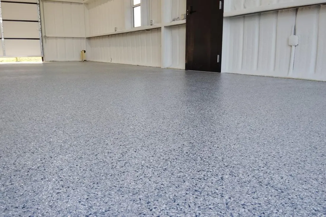 Grey speckled epoxy coating on a spacious garage floor with white paneled walls