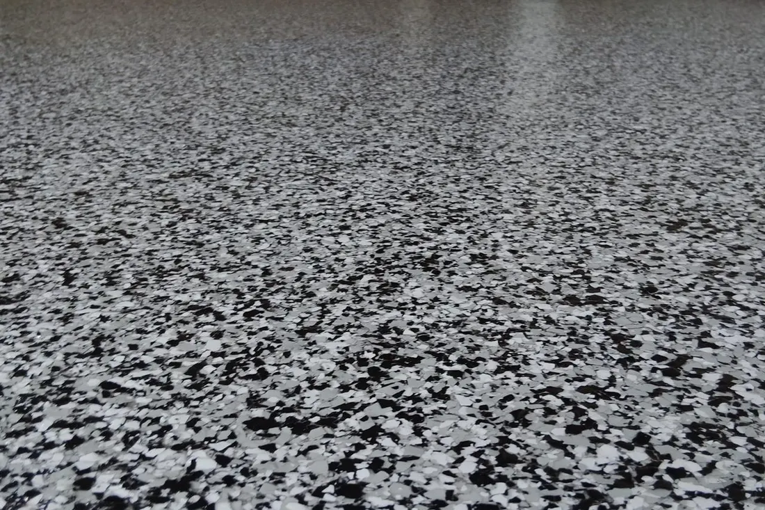 Glossy epoxy garage floor coating with a speckled pattern of black, white, and gray flakes