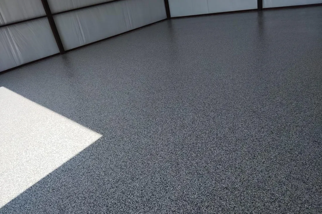 Smooth gray speckled epoxy coating applied over a concrete garage or workshop floor