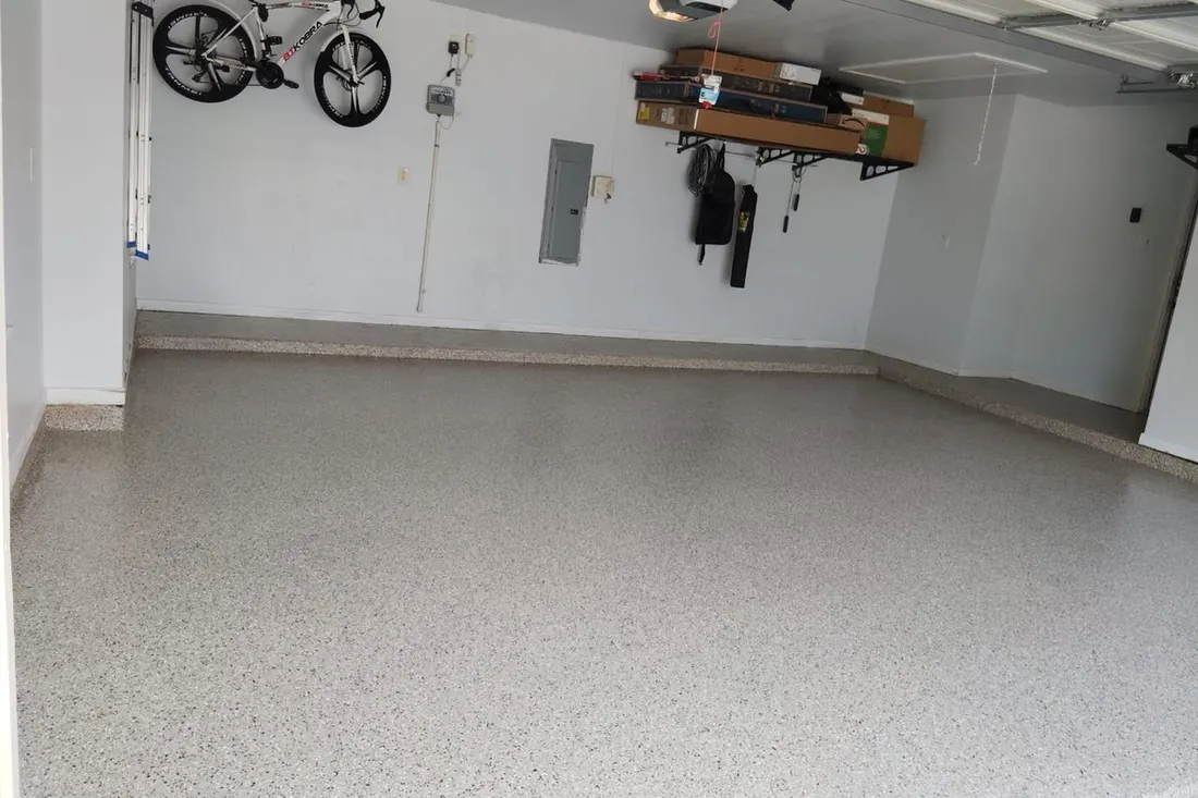 Spacious residential garage interior featuring speckled gray epoxy coated concrete flooring and white walls