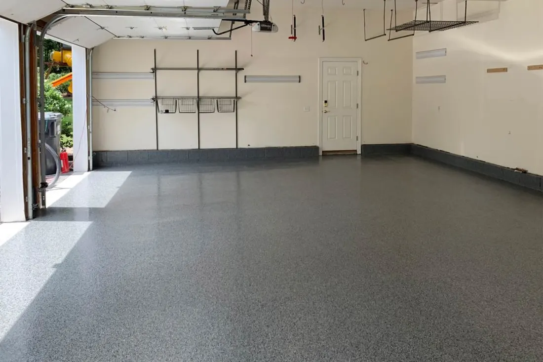 Spacious empty garage interior featuring a glossy speckled gray epoxy-coated concrete floor and white walls