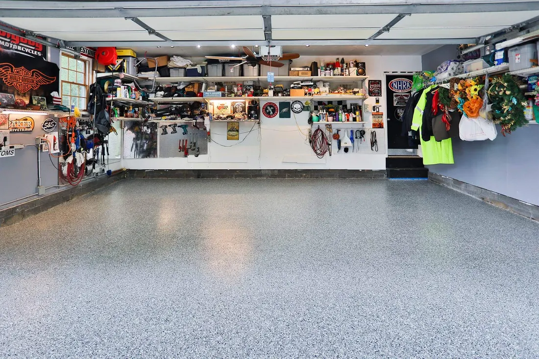 Speckled gray epoxy coated concrete floor in an organized residential workshop garage