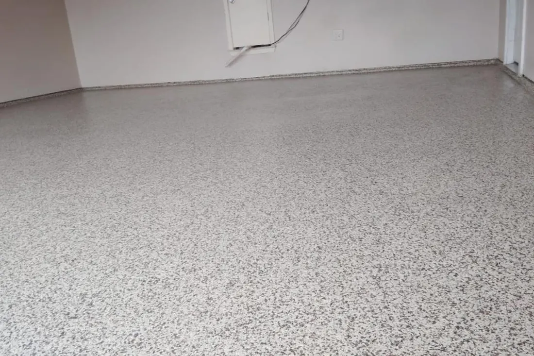 Garage interior with a gray speckled epoxy coated floor and plain white walls
