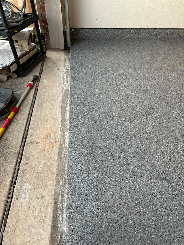 Gray flecked epoxy coating applied to a garage concrete floor meeting the outer threshold