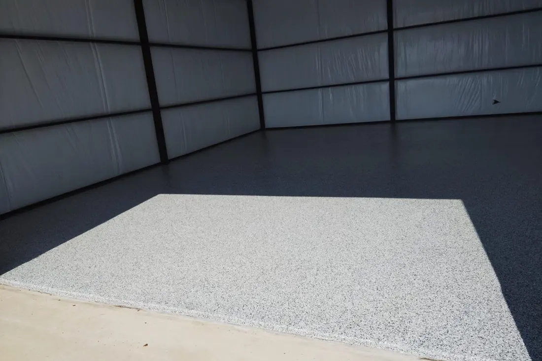 Gray speckled epoxy coating on the concrete floor inside an empty metal garage building