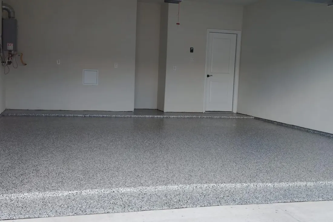 Empty garage interior with a gray speckled flake floor coating and white walls