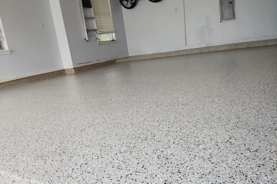 Speckled gray epoxy floor coating across a clean, spacious garage with white walls