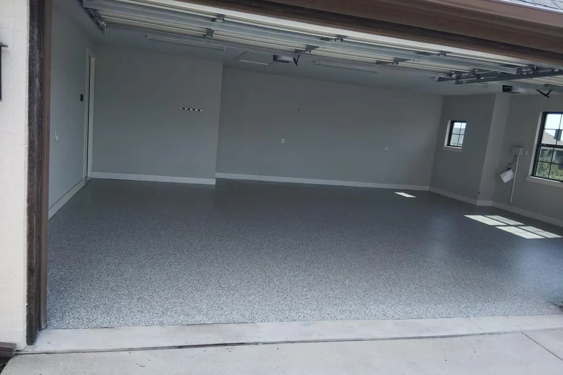 Empty garage interior featuring a glossy speckled gray coated concrete floor and light gray walls