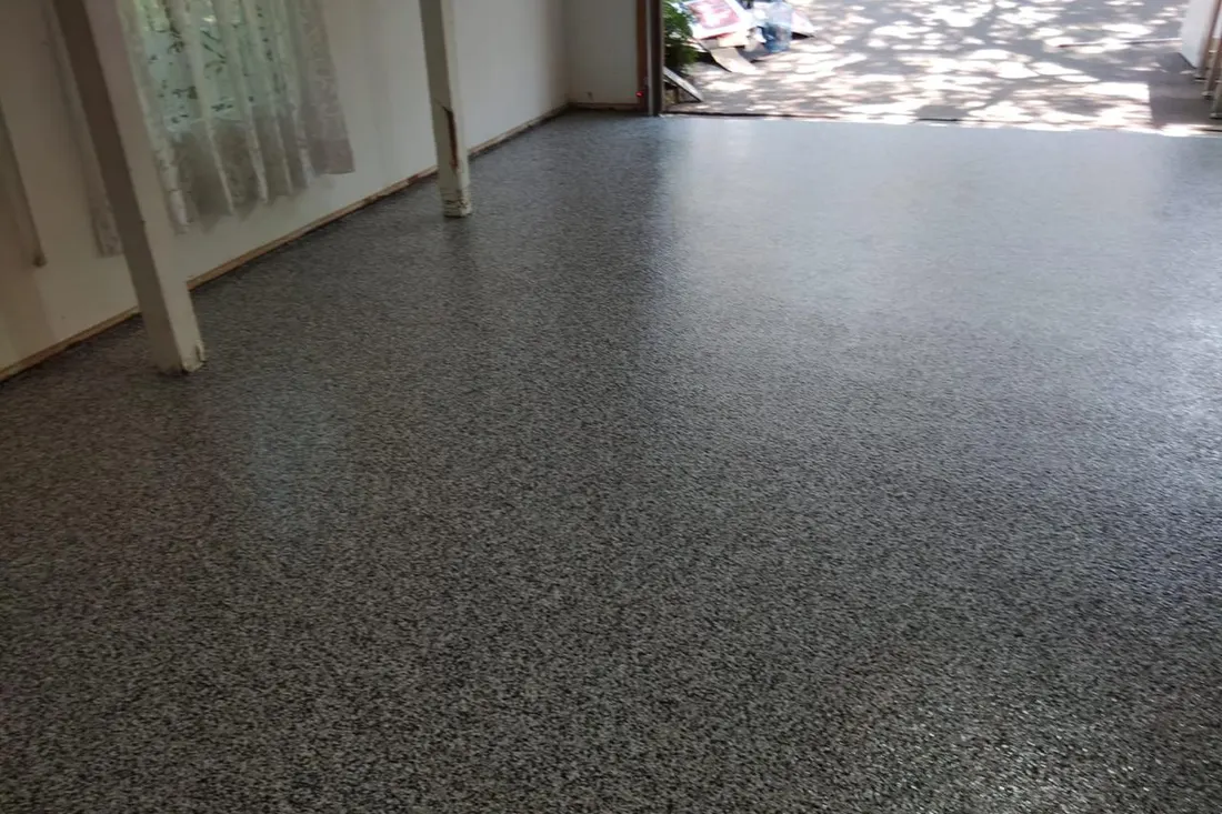 Gray speckled epoxy coating applied across the concrete floor of an open garage interior