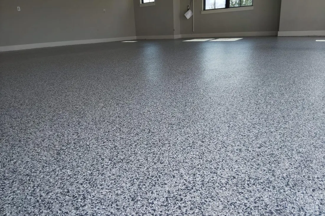 Spacious empty garage interior featuring glossy gray speckled coated concrete flooring