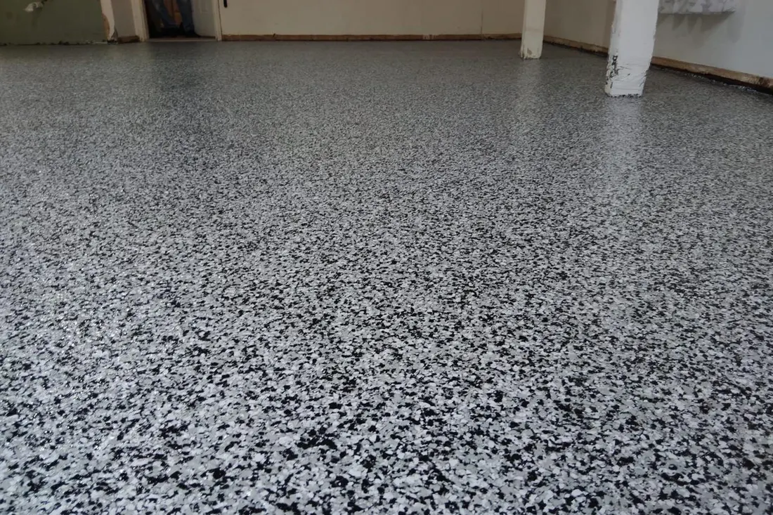 Spacious garage interior featuring glossy concrete flooring finished with speckled black, white, and gray flakes