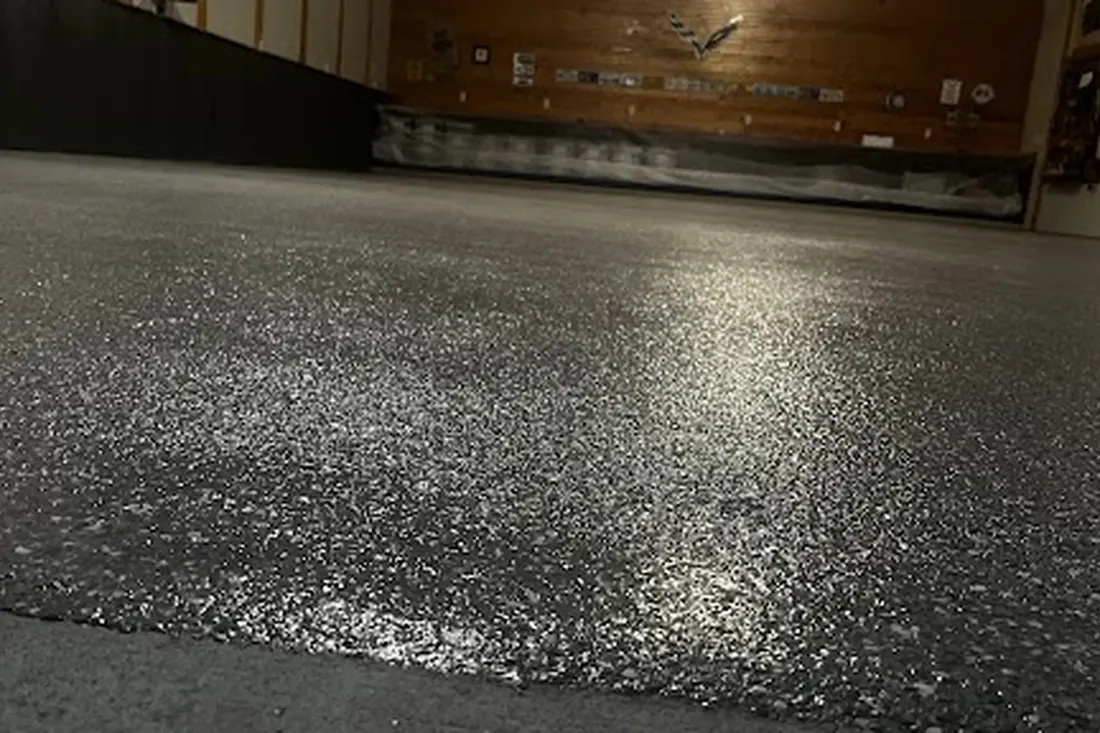 Glossy textured gray speckled epoxy coating on a spacious interior garage floor