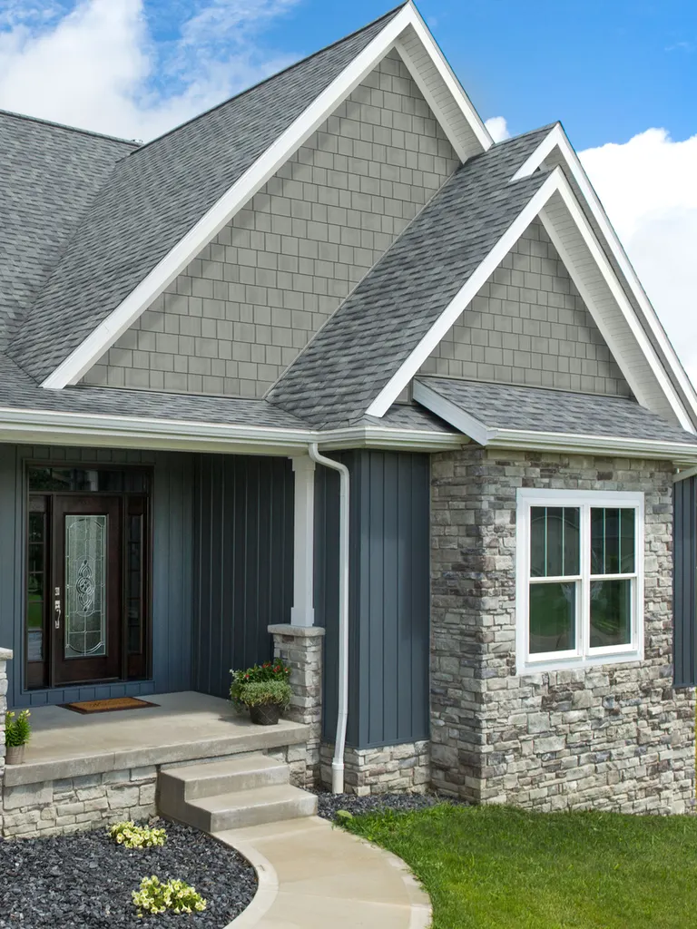 Home exterior with gray shingle gables, dark blue vertical siding, and gray stone veneer