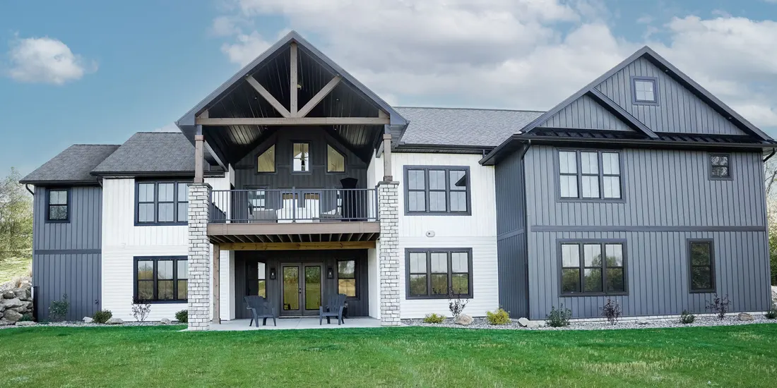 Two-story modern home featuring gray vertical siding, white insulated horizontal siding, and stone-accented patio pillars