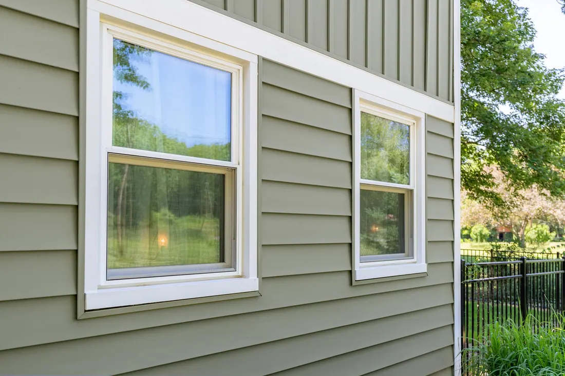Olive green horizontal and vertical siding on house exterior with white trimmed windows