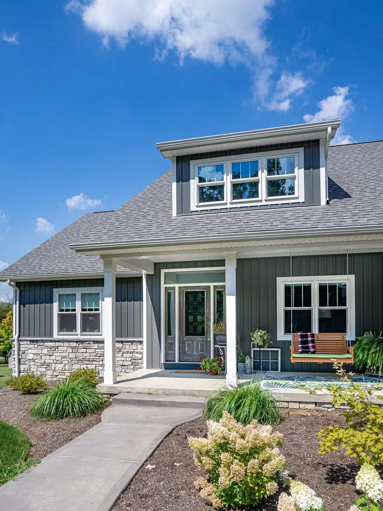 Dark gray vertical siding and light stone veneer on a house with covered front porch
