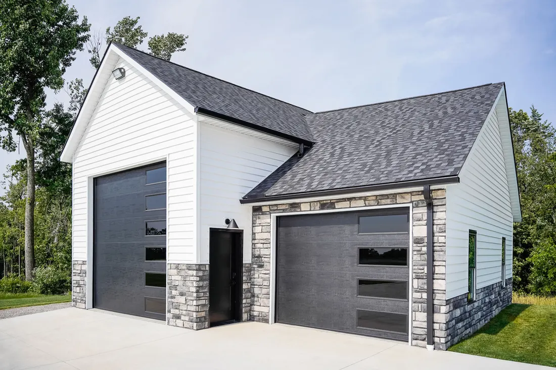 White insulated siding and gray stone veneer on a garage with black modern doors