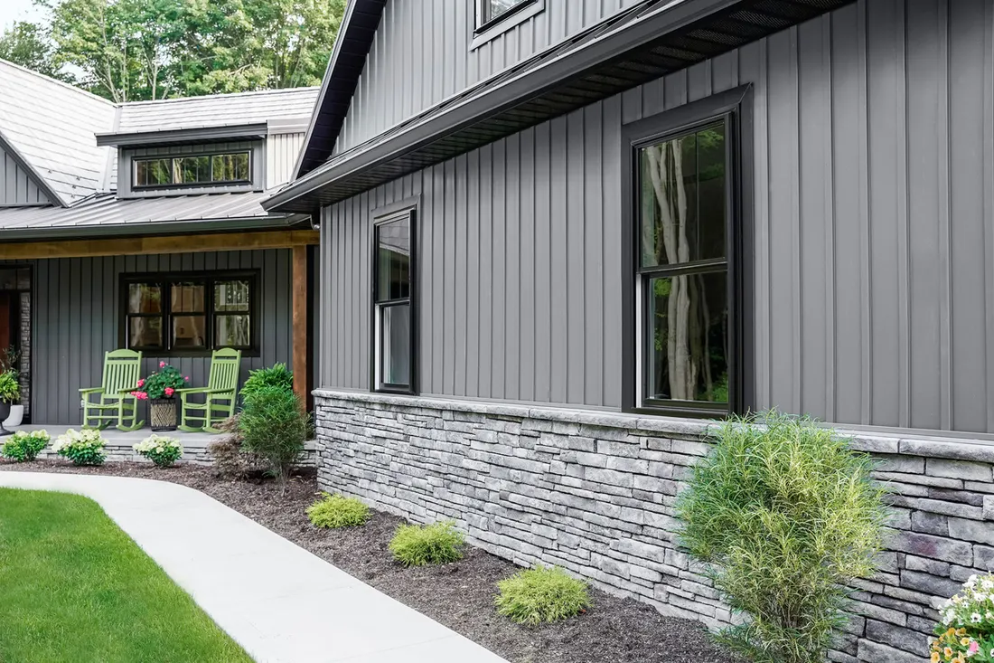 Charcoal vertical insulated siding and gray stone veneer on a modern house exterior