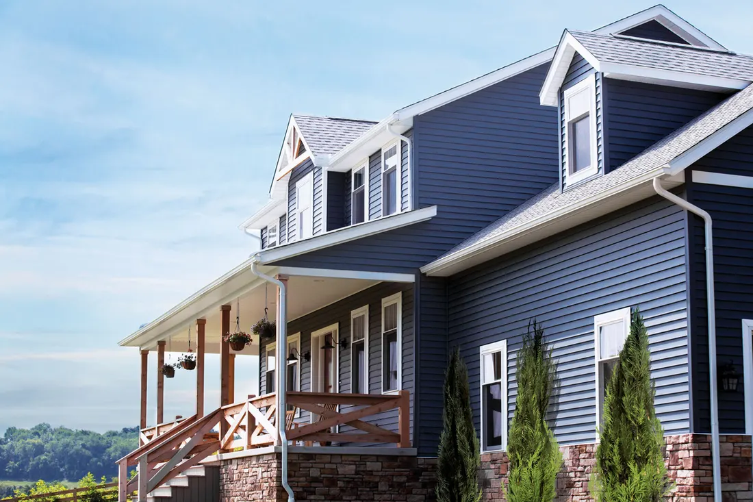 Dark blue vinyl siding on a two-story home with white trim and a stone foundation