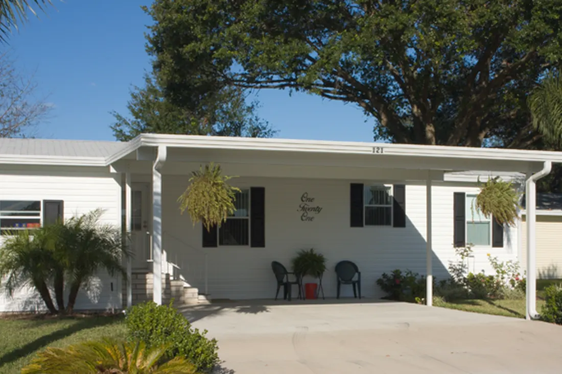 Attached white metal carport over a concrete driveway outside a white residential home