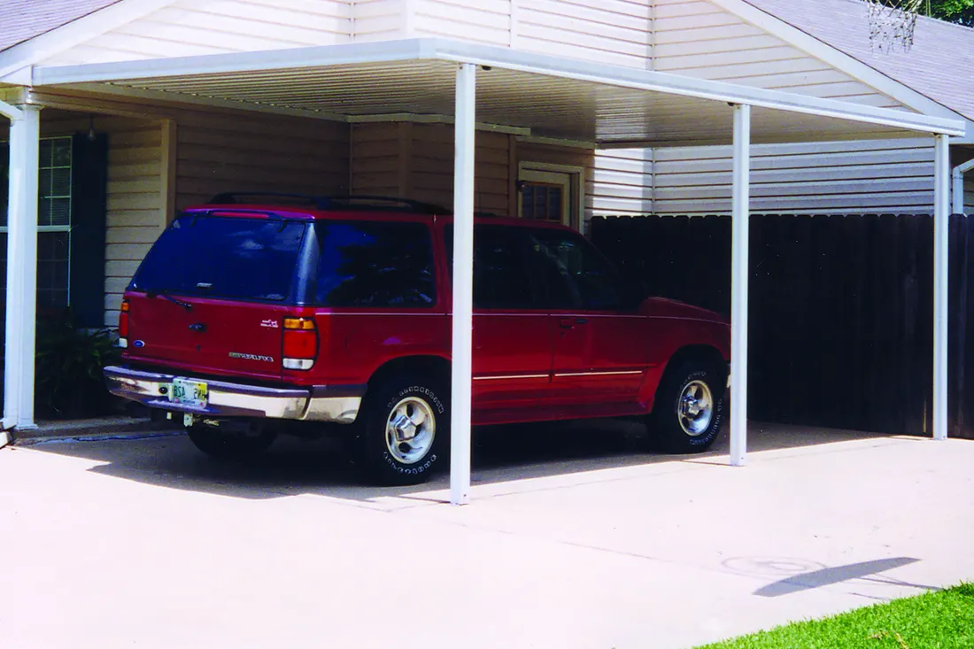 White metal carport structure sheltering a red SUV in a concrete driveway