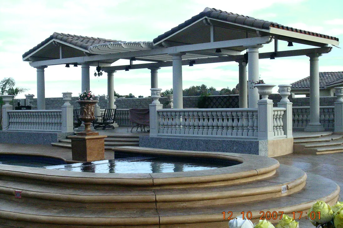 Tiled patio cover with white columns and balustrades overlooking a tiered backyard pool
