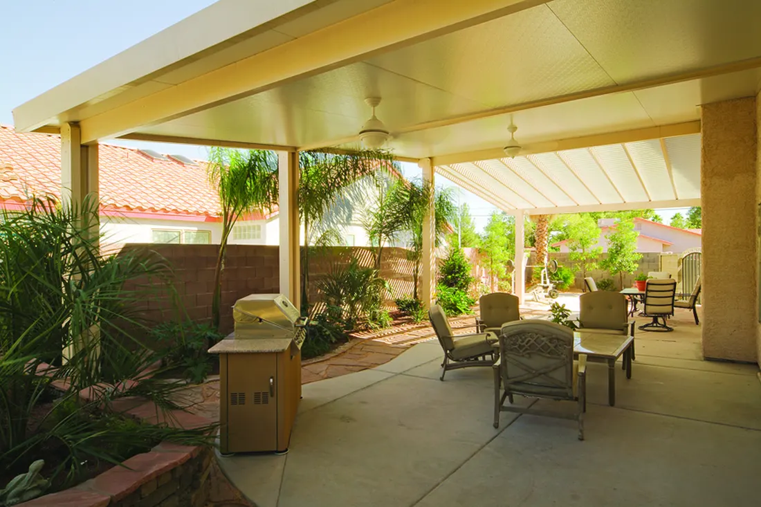 Tan solid patio cover with ceiling fans over a backyard concrete patio with seating