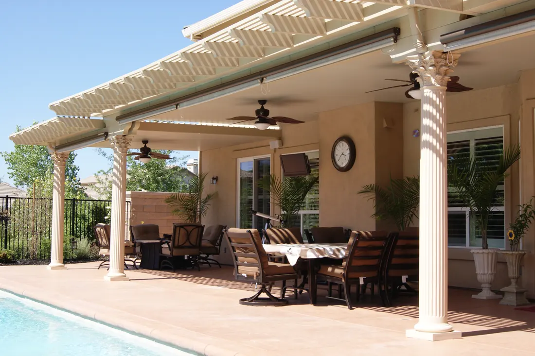 Attached beige patio cover with classical fluted columns over a poolside dining area