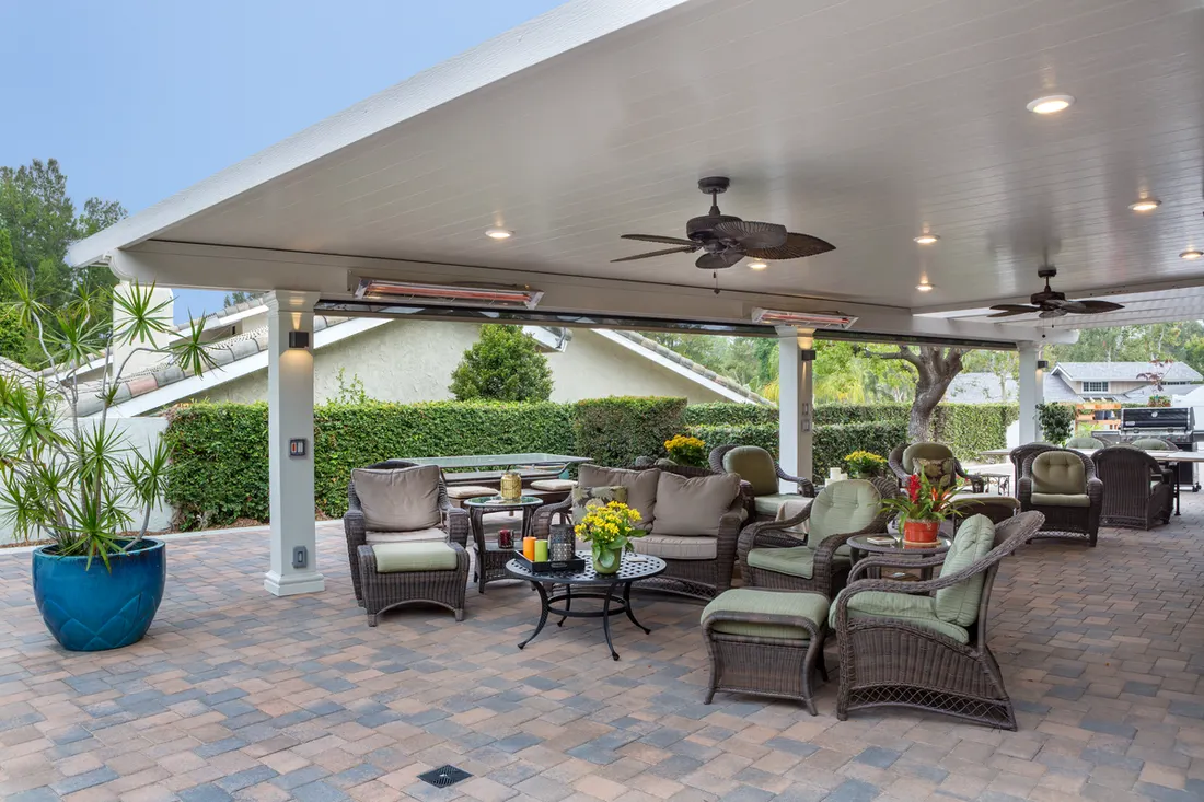 White solid patio cover with ceiling fans, recessed lights, and heaters over a paved patio with furniture