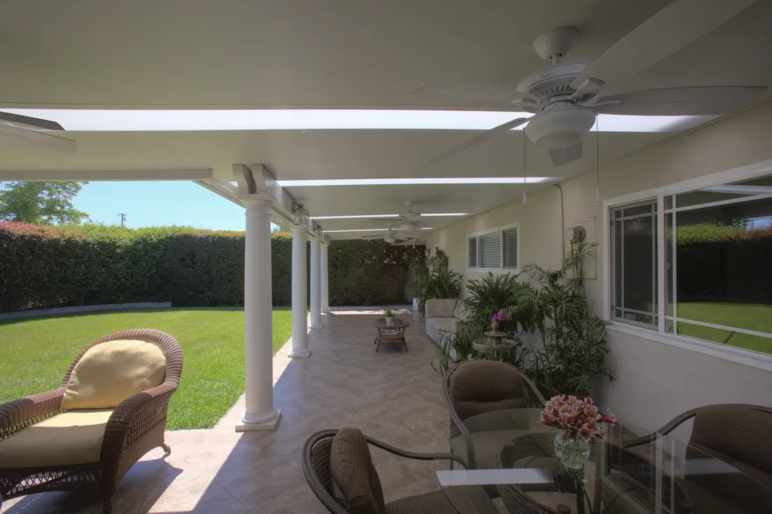 White patio cover with ceiling fans supported by round columns over a tiled outdoor living space