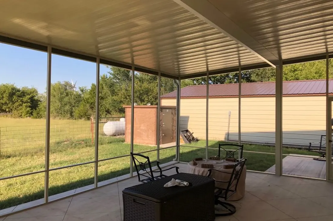 Screened-in patio enclosure with metal roof, tiled floor, and outdoor furniture overlooking a grassy yard