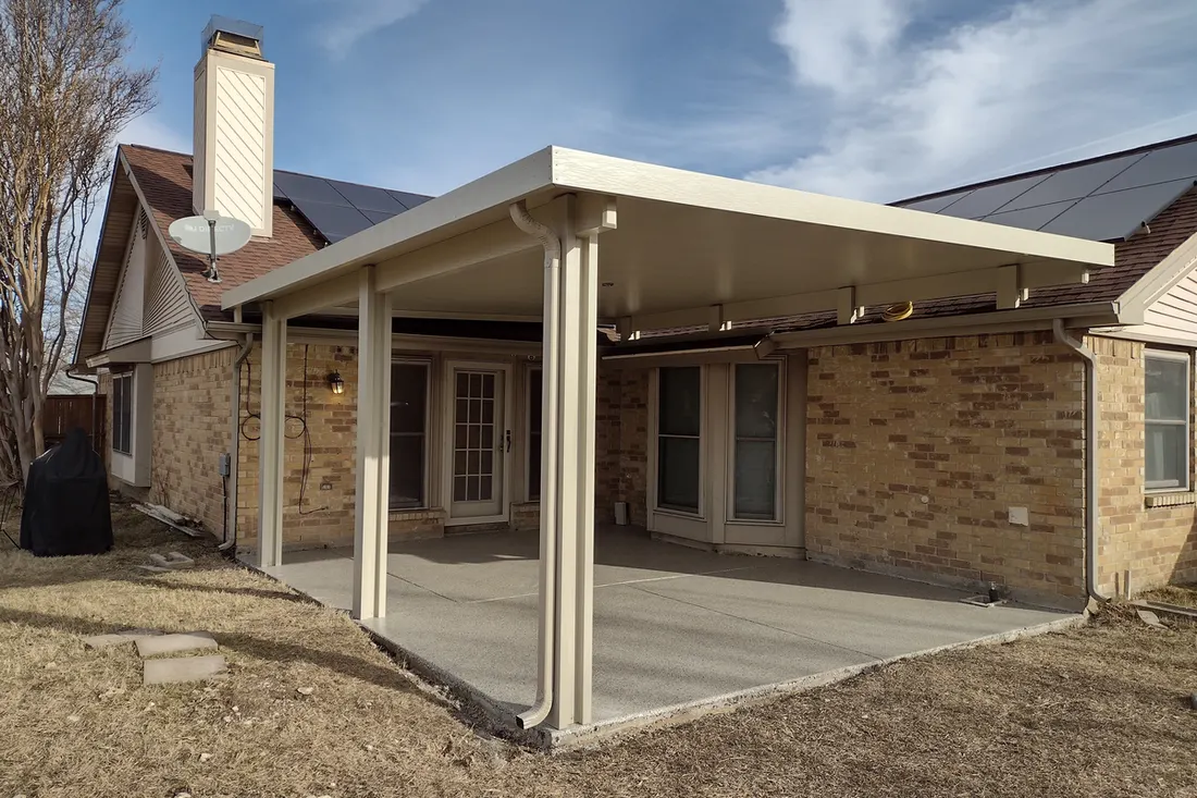 Covered patio with smooth gray coated concrete floor beside a tan brick house