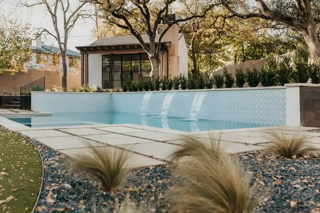 Modern pool with a tiled water wall and ornamental grasses