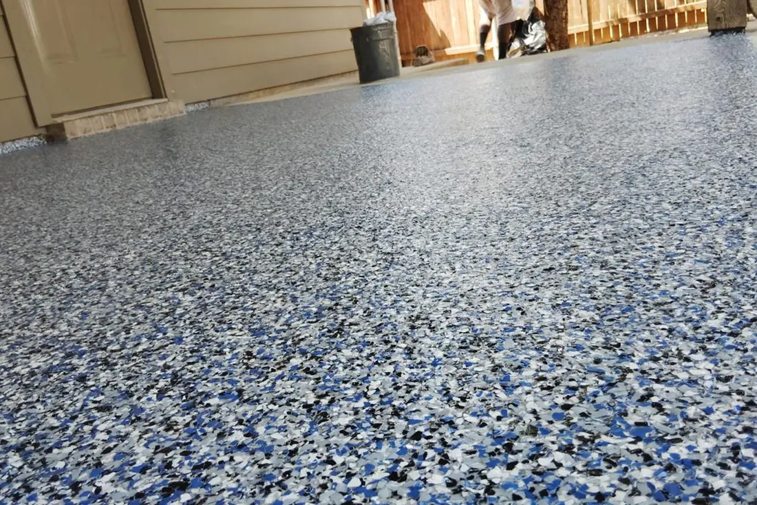 Speckled blue, white, and gray coated patio floor beside beige siding and a doorway
