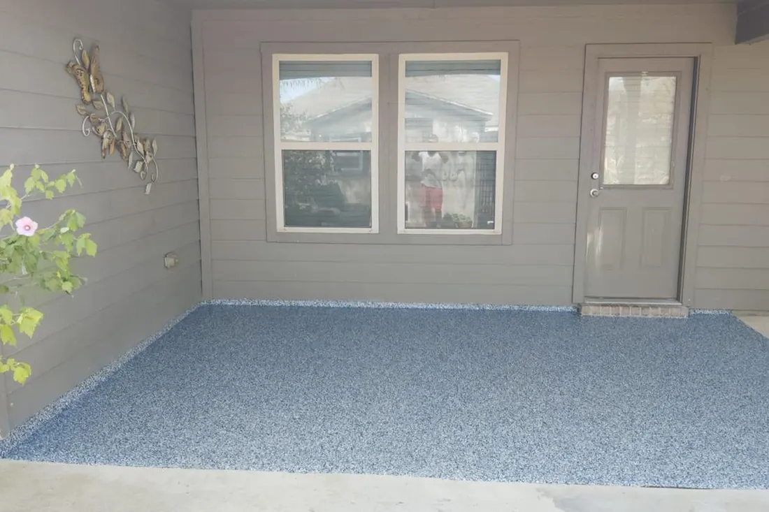 Covered patio featuring fresh blue speckled epoxy floor coating beside a gray-sided home exterior