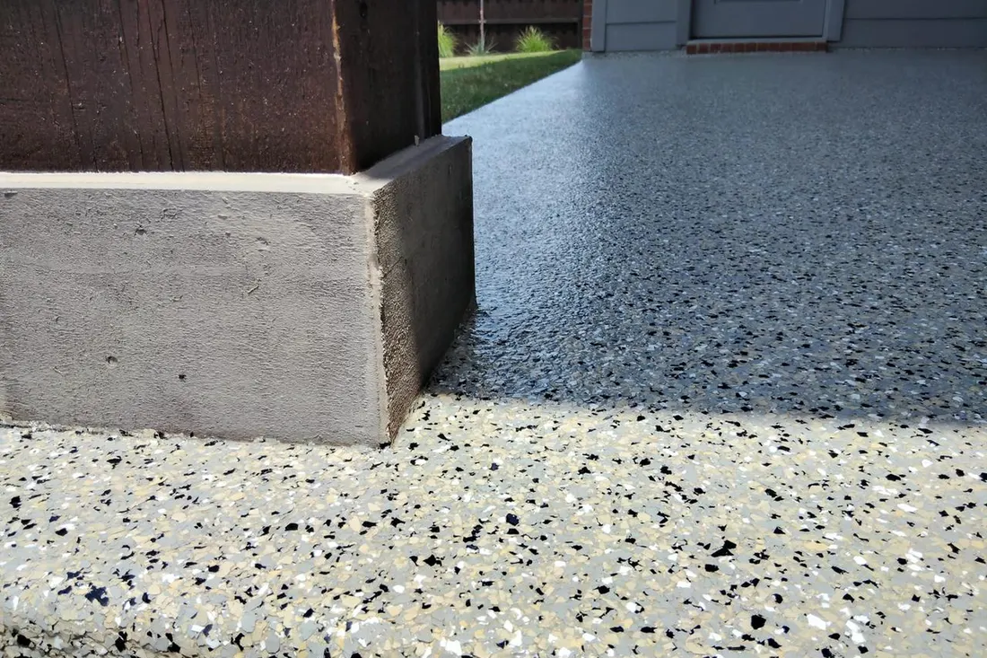 Speckled gray patio floor coating beside a concrete step and dark wooden post