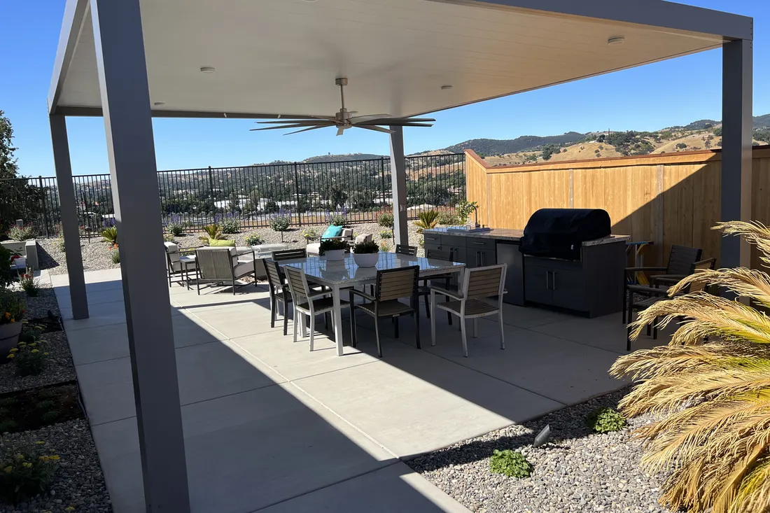 Modern gray pergola with ceiling fan, dining set, grill, and mountain-view patio