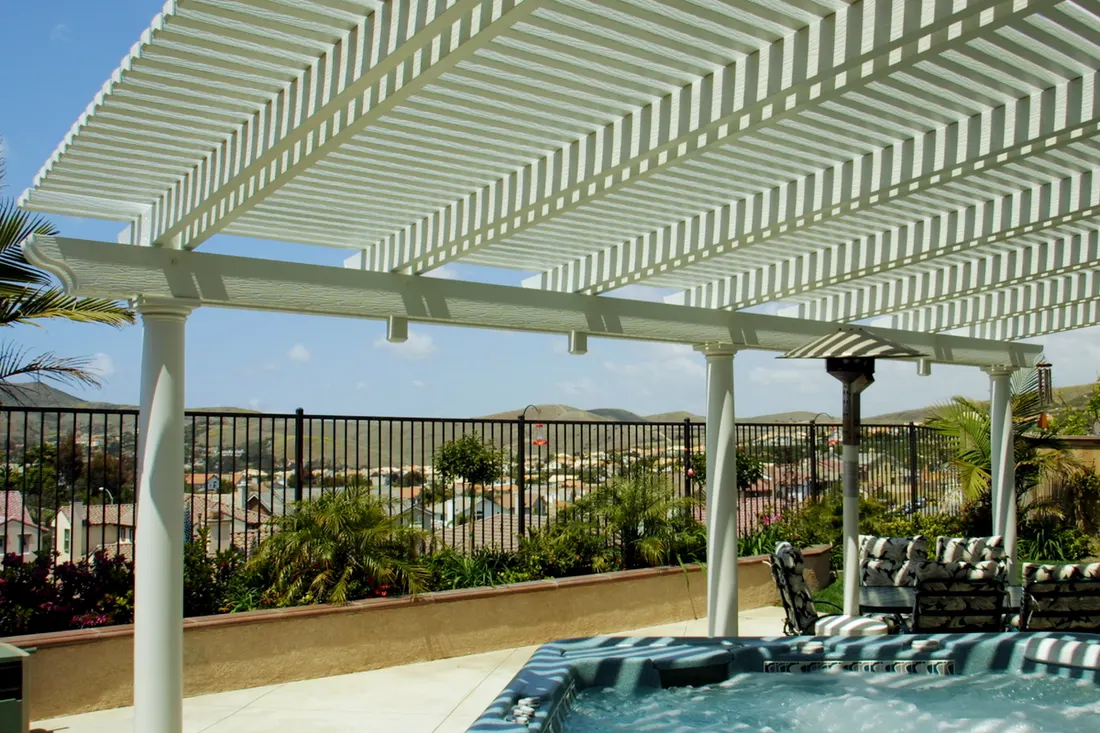 White louvered patio pergola shading an outdoor hot tub and seating area overlooking a valley