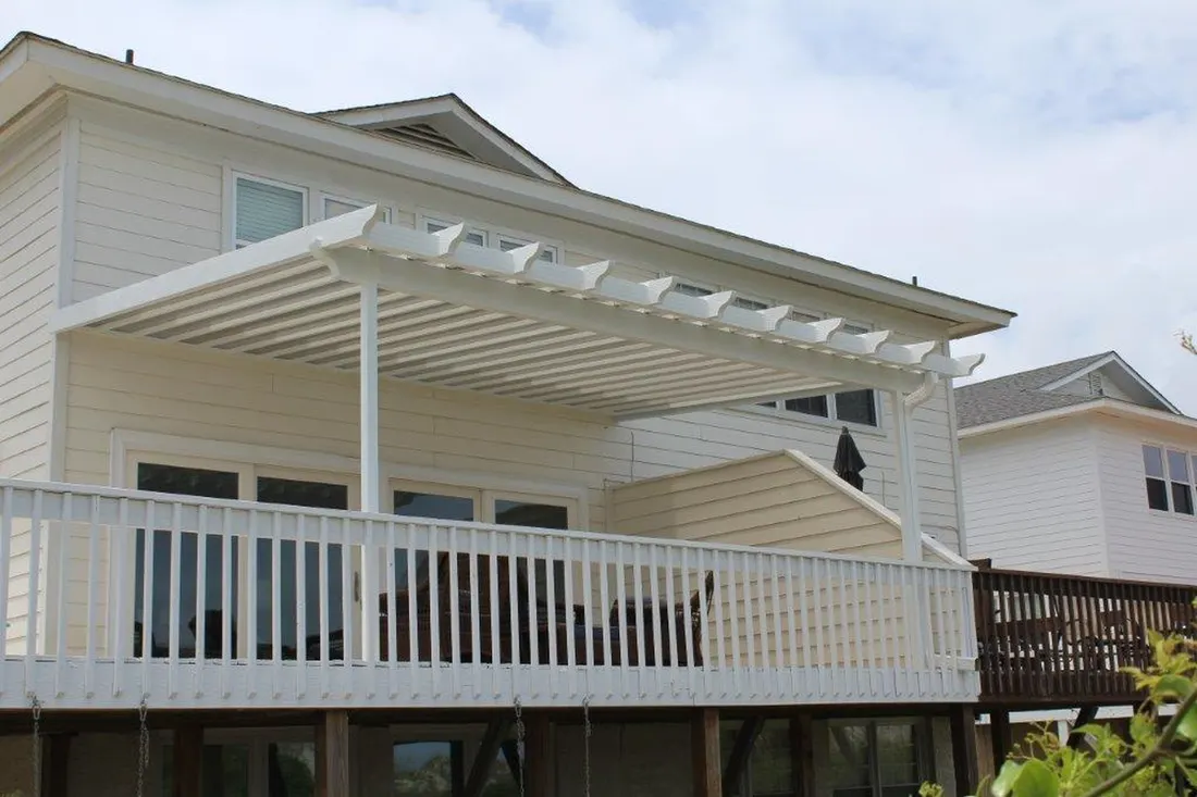 White louvered pergola attached to an elevated deck on a two-story home