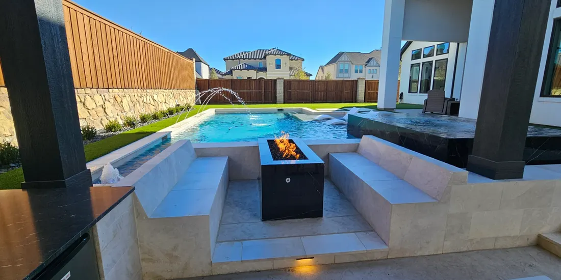 Modern backyard pool with raised spa, sunken seating, tiled fire feature, and stone walls