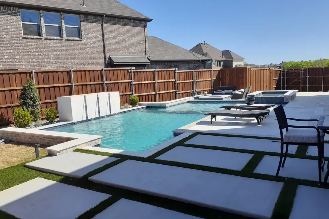 Backyard swimming pool with turquoise water, fenced patio, concrete pavers, and lounge furniture