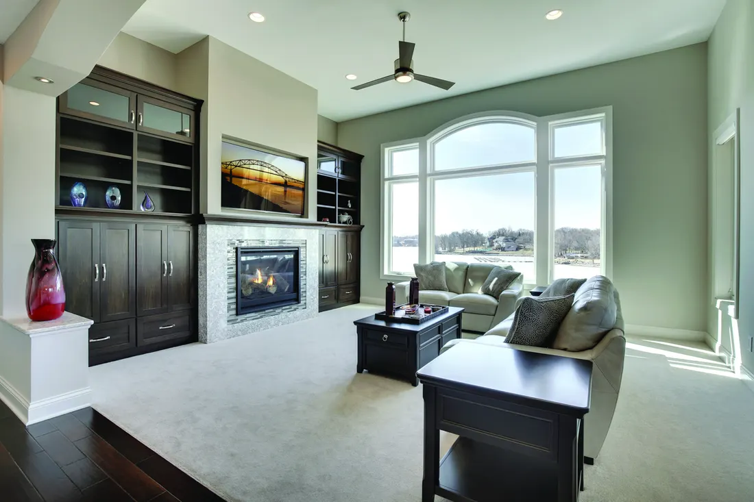 Living room with large white arched picture windows overlooking a scenic lake view