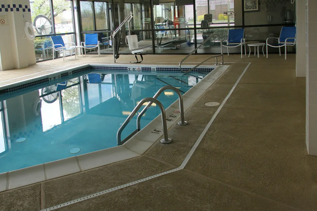 Indoor pool with a speckled coated deck under a screened enclosure
