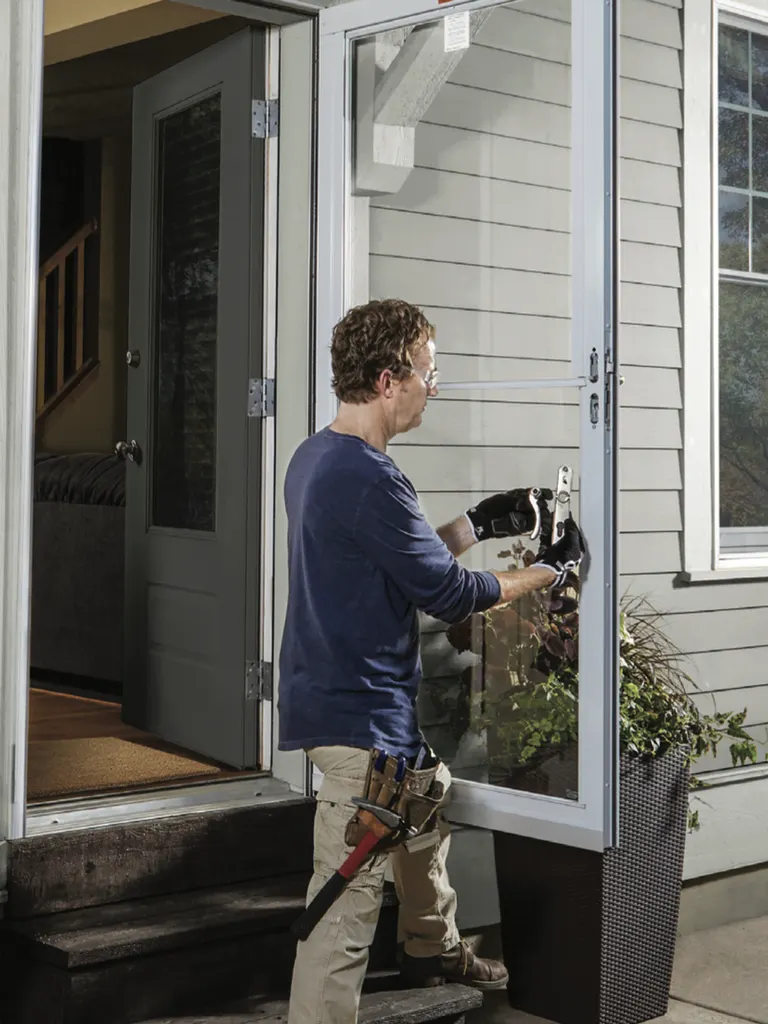 Installer setting a glass storm door at a home's side entry